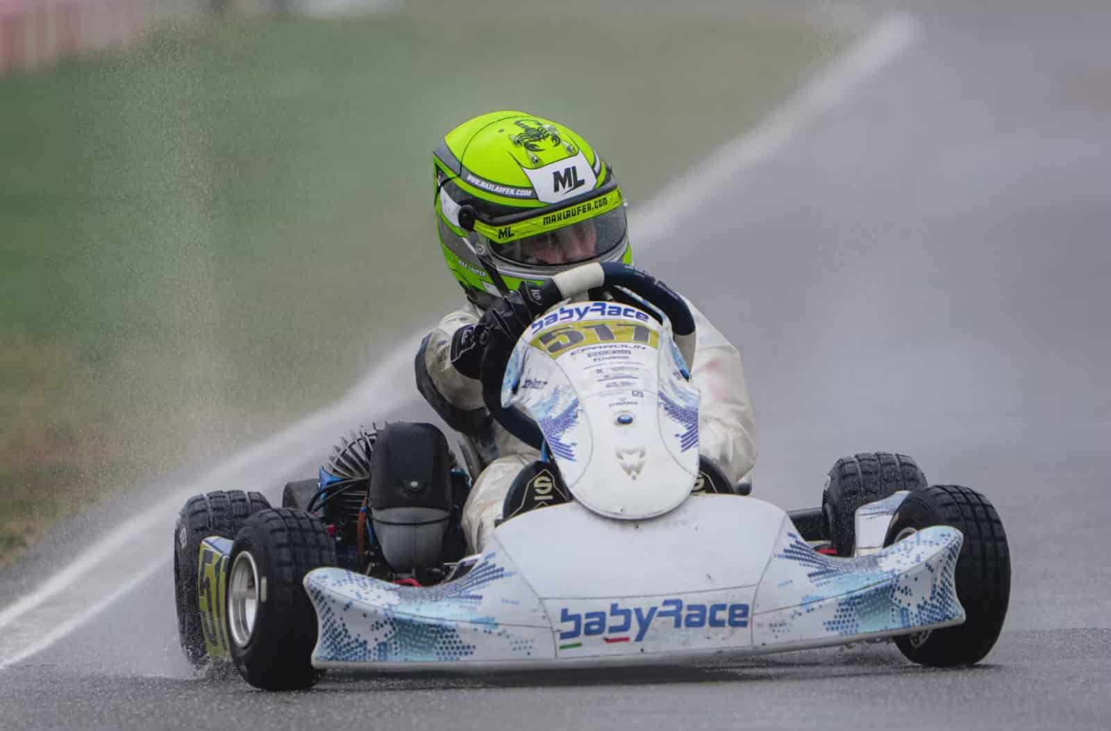 Babyrace kart racing through spray on a wet track that is starting to dry