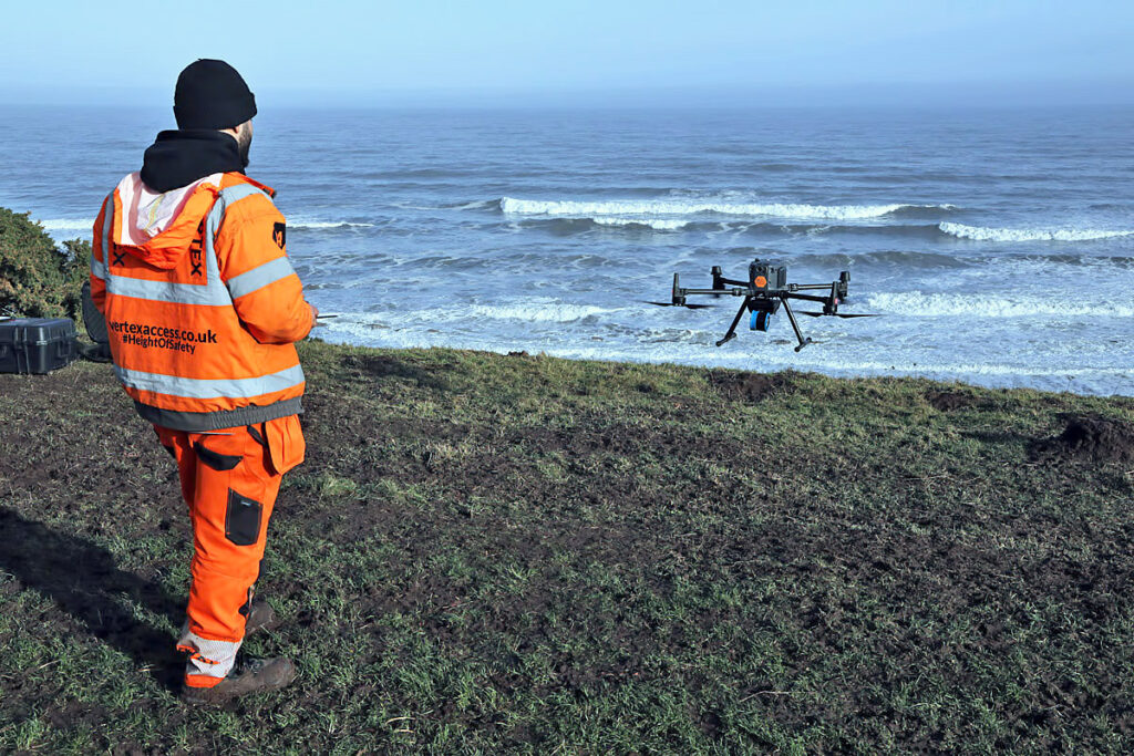 A drone operator holding a controller trackside at a karting circuit