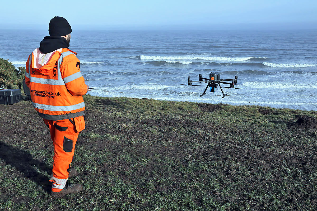 A drone operator holding a controller trackside at a karting circuit