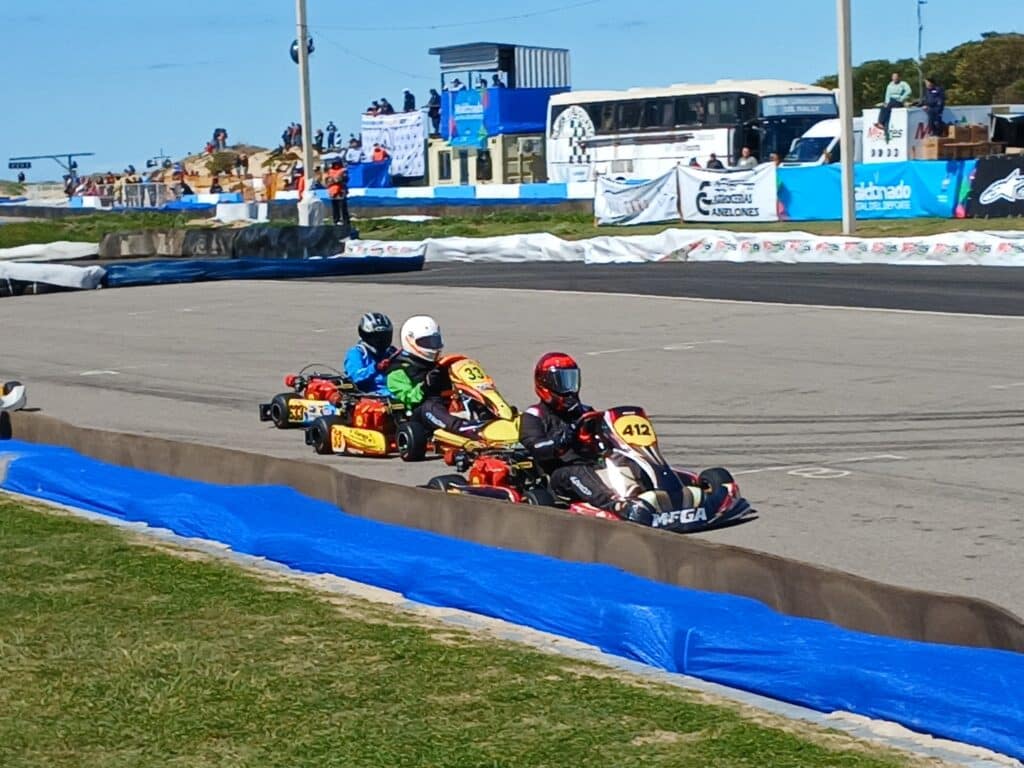Karts running nose to tail in a tight pack on track