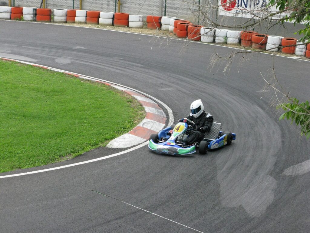 Kart through a hairpin with a rubbered-in band of asphalt visible away from the geometric line