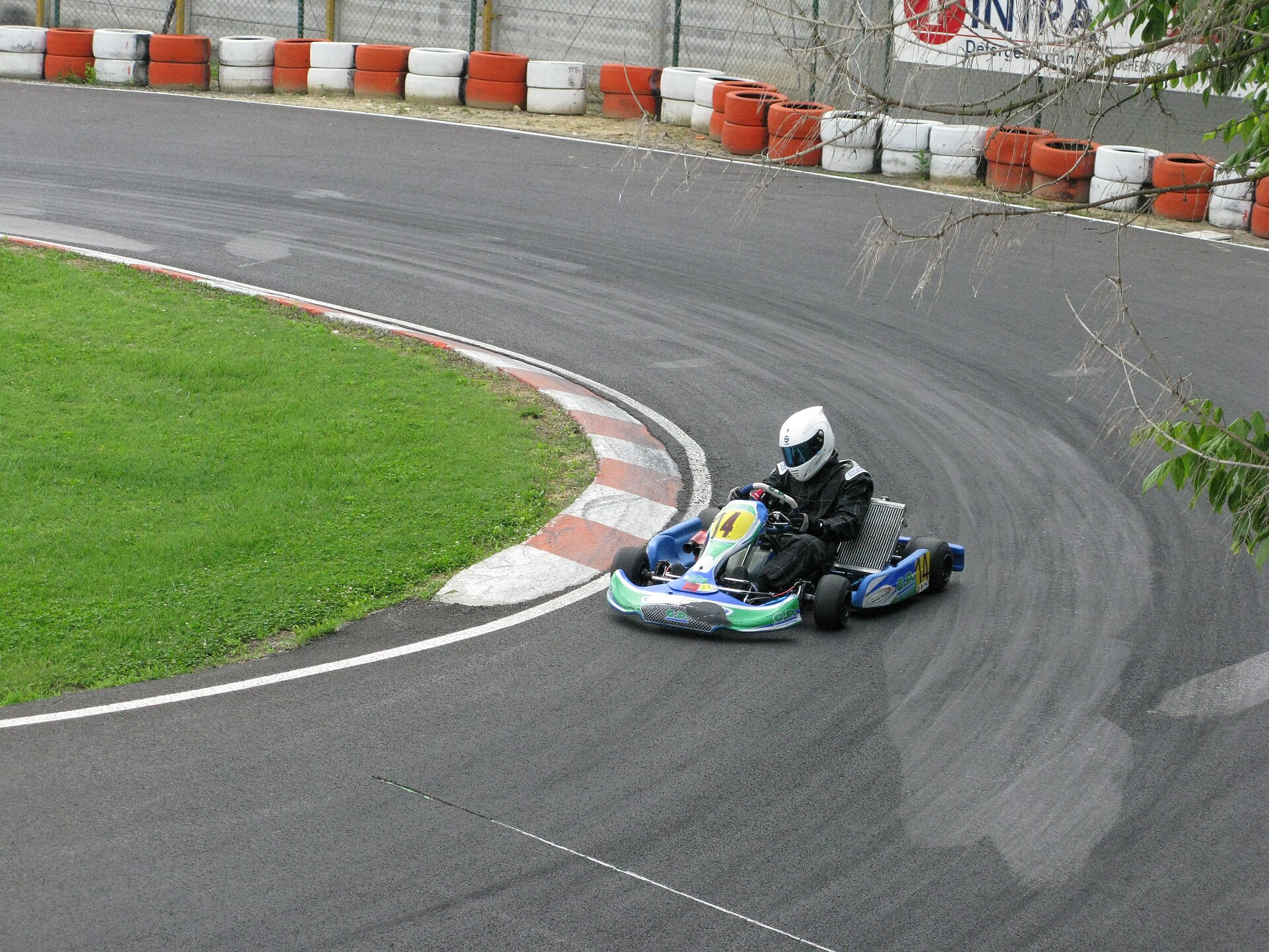 Kart through a hairpin with a rubbered-in band of asphalt visible away from the geometric line