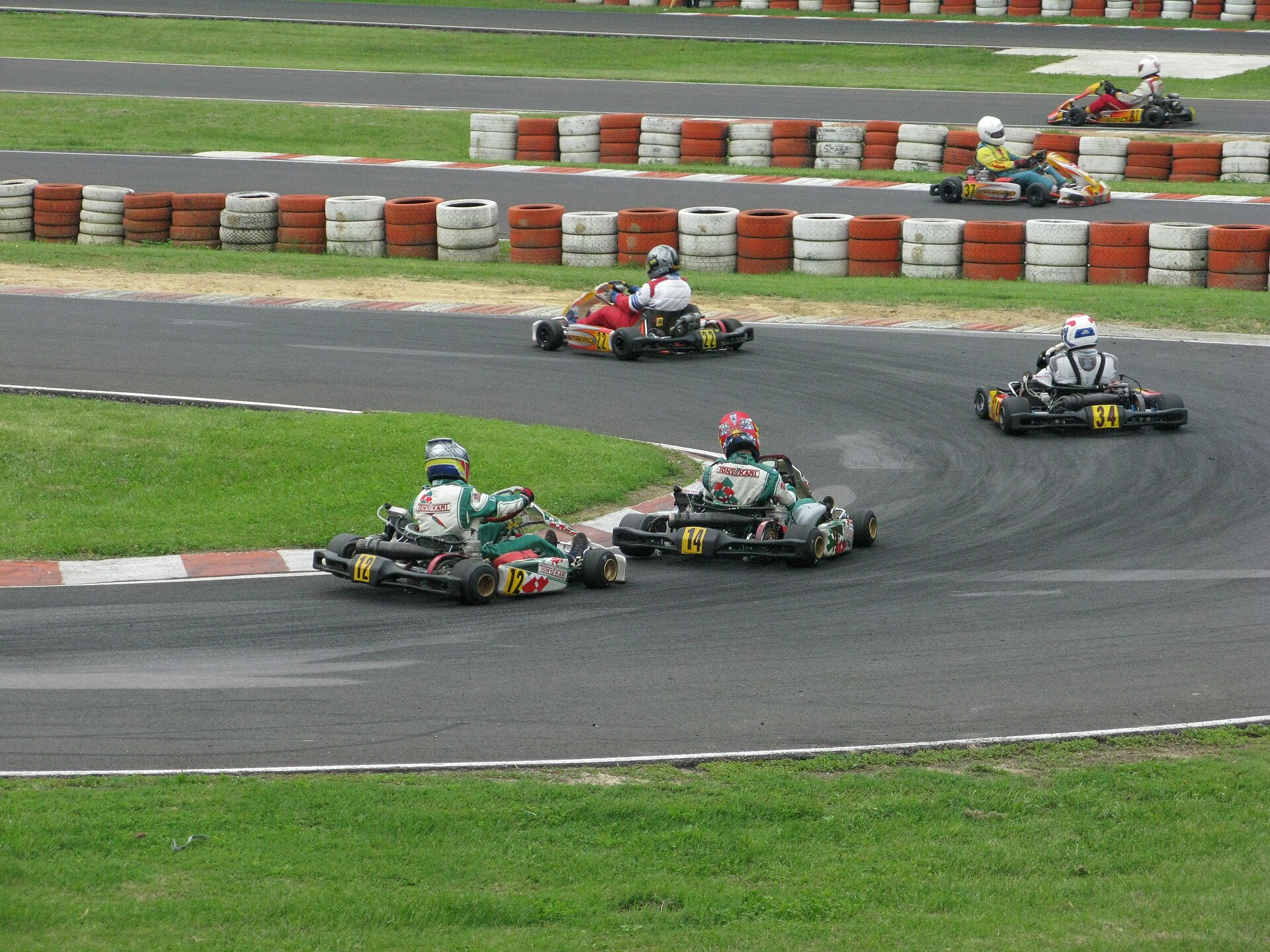 Karts cornering with the inside kerb in use, wheels running right at the kerb edge