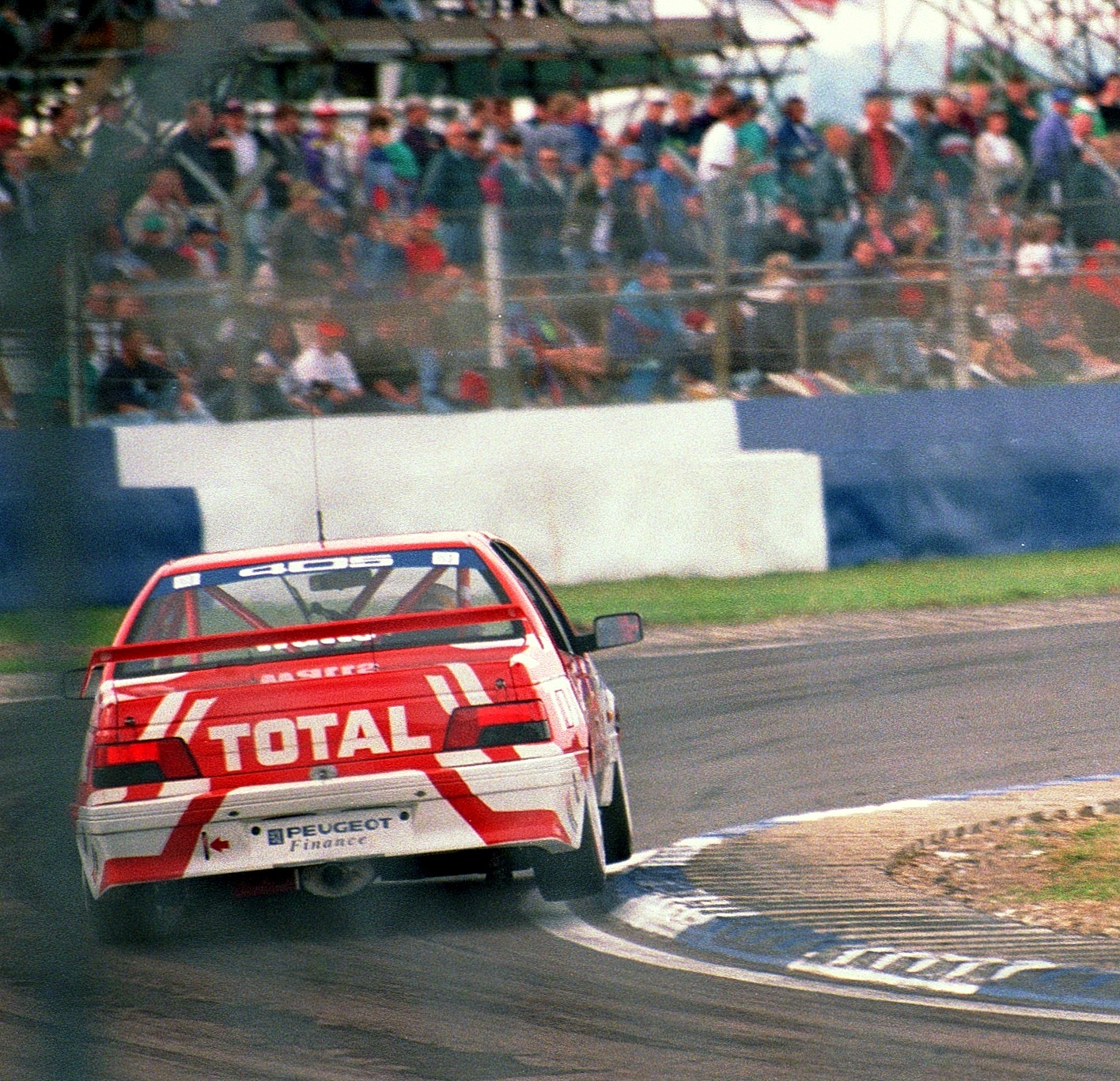 Touring car riding the flat kerb at Luffield with its inside wheels raised