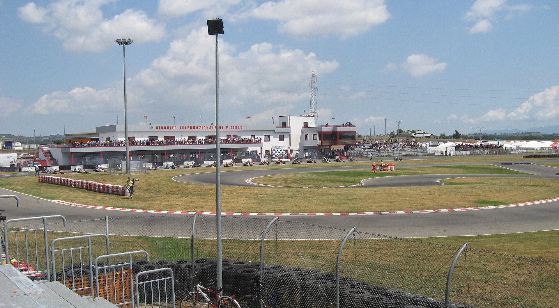 Wide panorama of Circuito Internazionale di Viterbo with a packed pit balcony and karts on track