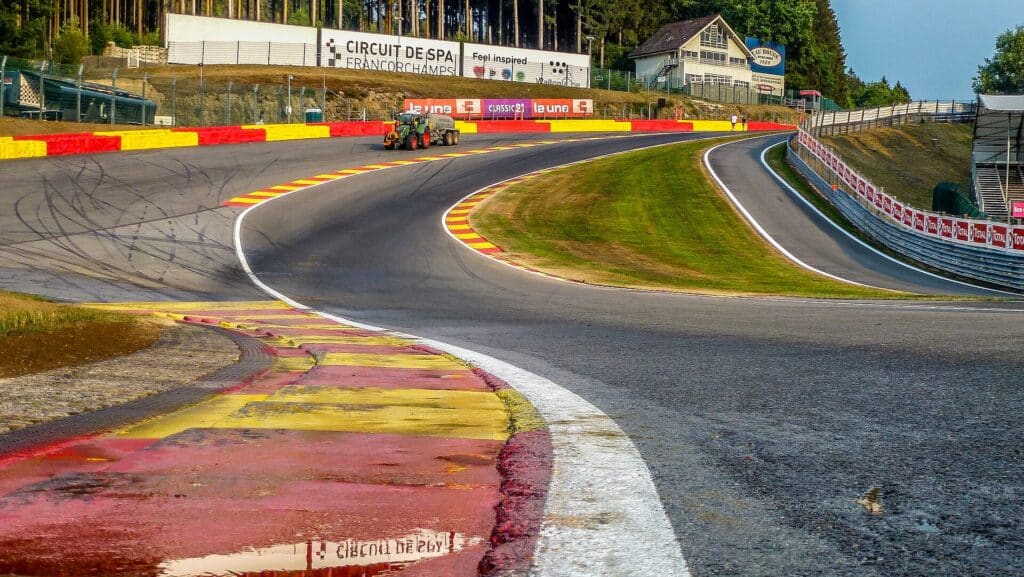 The Eau Rouge and Raidillon complex at Spa-Francorchamps seen from track level, showing the steep uphill climb and the red and yellow kerbs