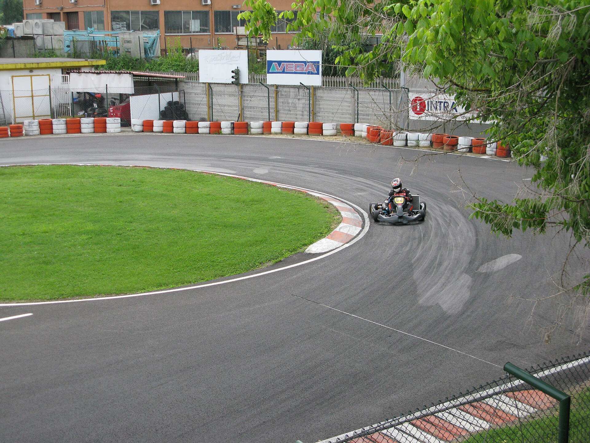 Elevated view of a hairpin with tarmac banded by dark rubbered-in strips and pale unused asphalt